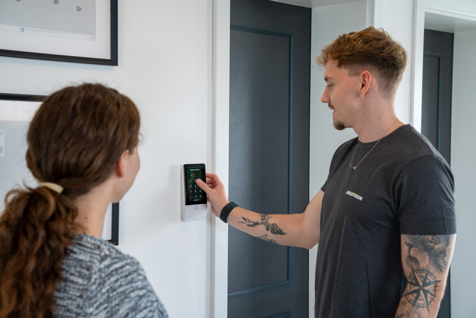 Instalator pokazuje klientce obsługę klawiatury systemu JABLOTRON w domu